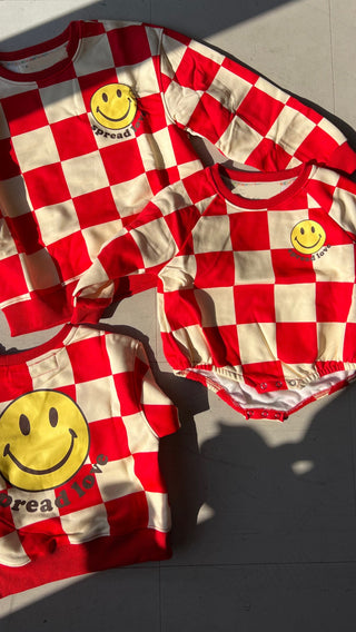 Red and white checkered outfit with smiley face logos on a light gray background